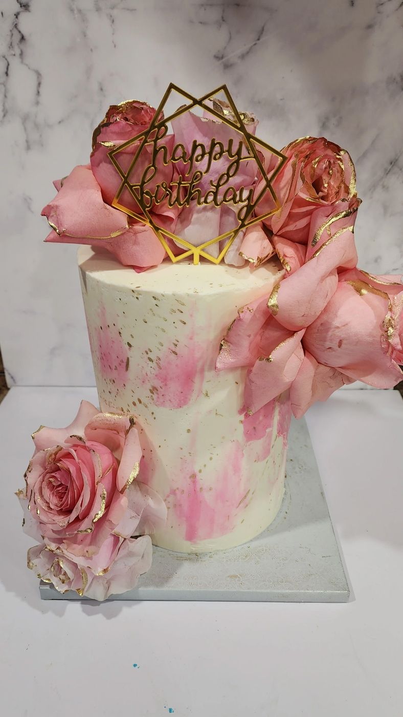 Pink watercolor birthday cake with sugar flowers and a gold geometric topper