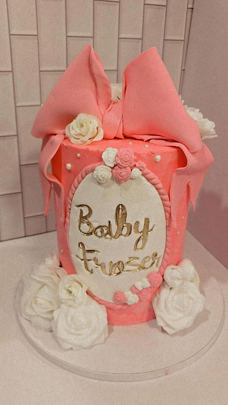 Coral baby shower cake with a fondant bow and white roses