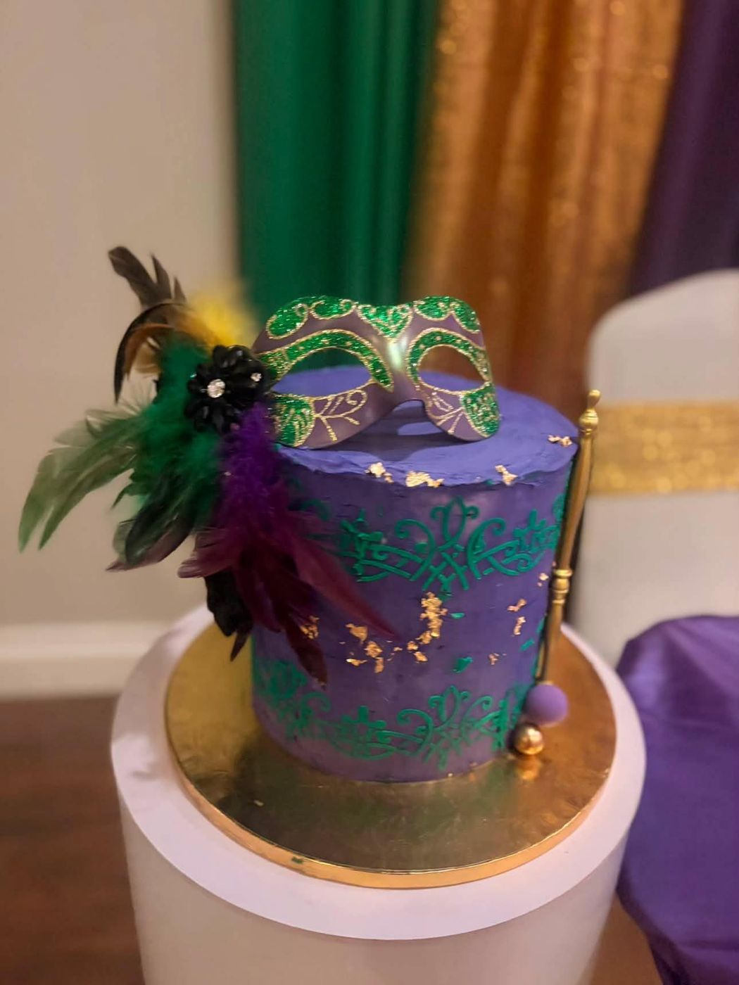 Purple masquerade-themed cake with a mask and feathers